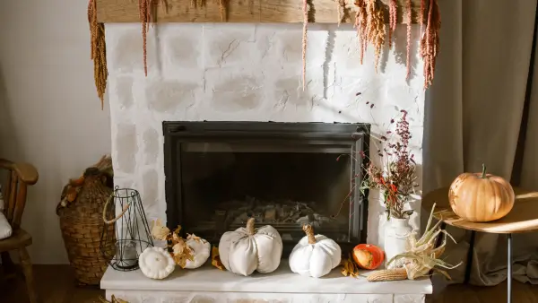A fireplace with fall pumpkins.