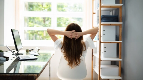 A person sitting at a home office, looking out a window.