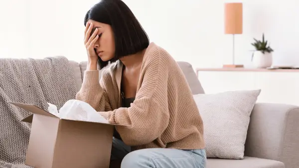 A person sitting on a couch, with their head in their hands.