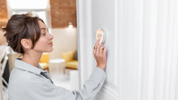 A person adjusting their smart thermostat.