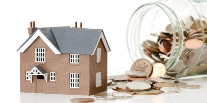 A small toy home next to coins