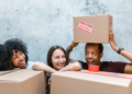 Three roommates pose in front of moving boxes
