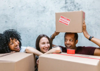 Three roommates pose in front of moving boxes