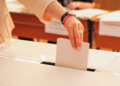 Someone casting a vote into a box.