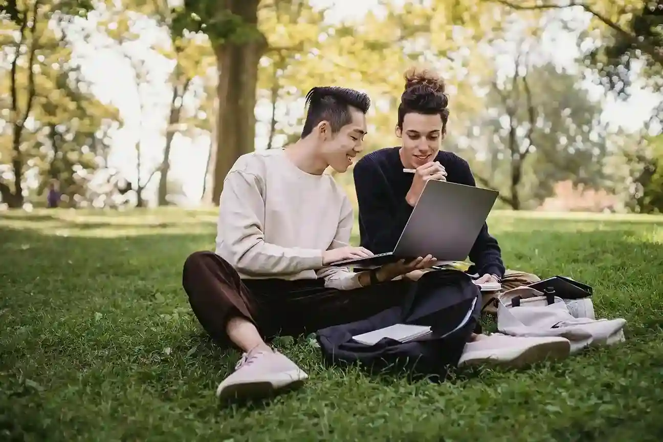university students in the grass reading a laptop