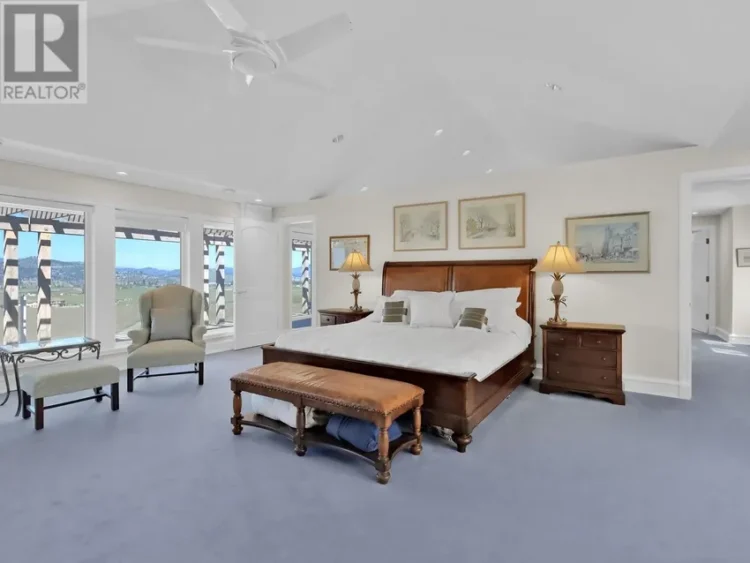 A well-furnished bedroom with a bed, a chair, and a ceiling fan.