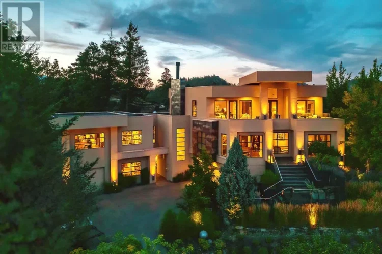 A large home with a spacious driveway surrounded by several trees.