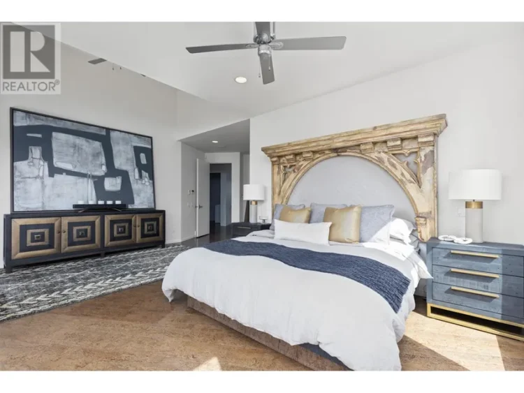 A bedroom with a large bed and an artwork displayed on the wall.