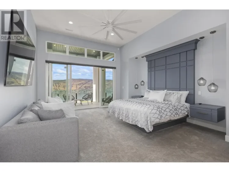 A spacious bedroom featuring a large bed and a balcony with outdoor seating.