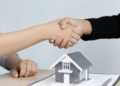 Two people shaking hands over a tiny house model