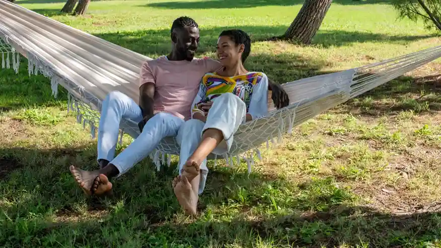 Two people sitting on a hammock together.