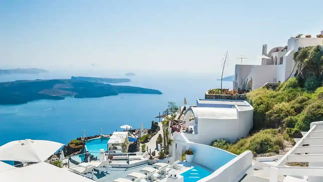 A scenic view of the sea and white buildings from a hilltop.