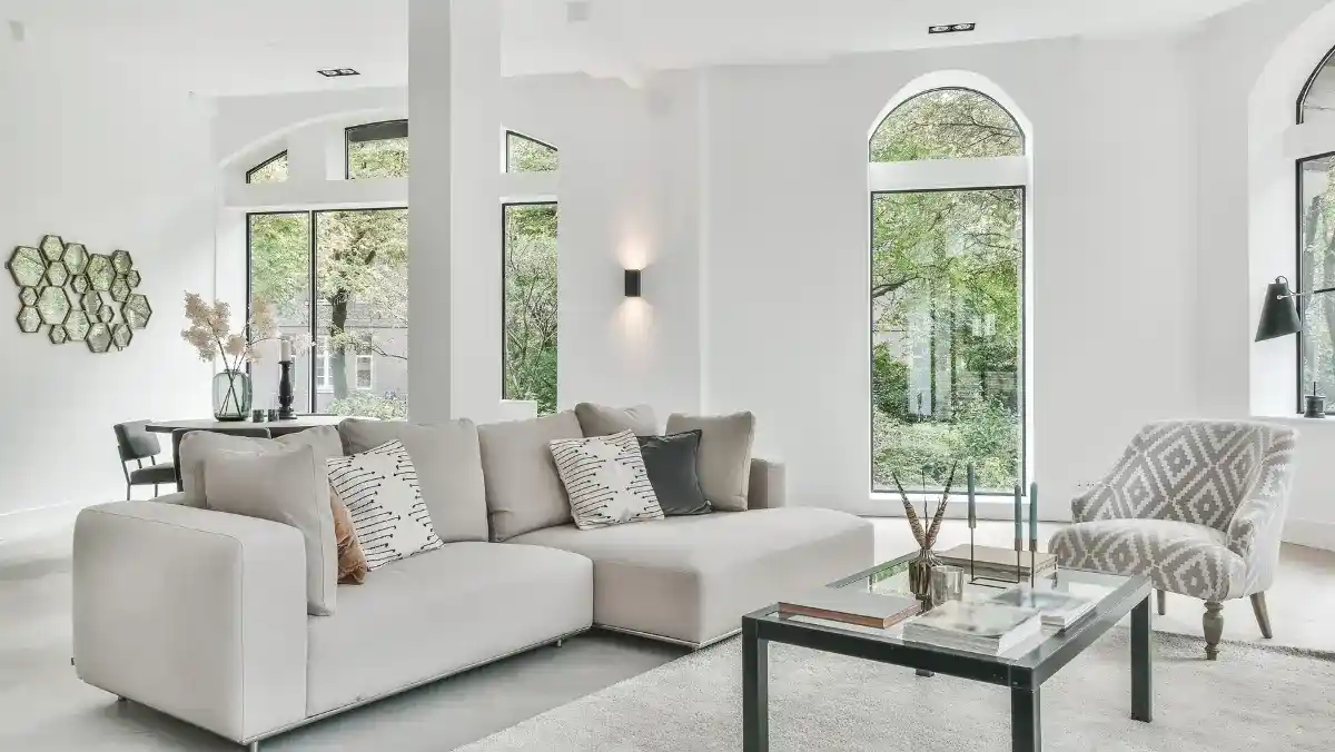 A spacious living room with stylish white furniture and large arched windows.