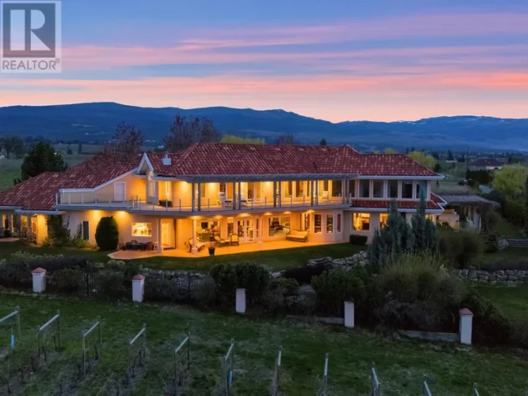 A large house with a red roof set against a mountain backdrop.