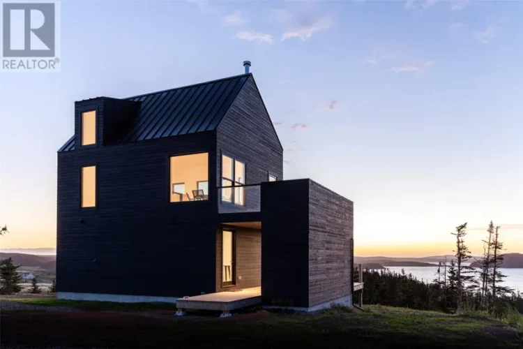 A modern black house on a hill.