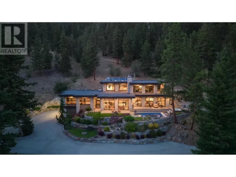A large mountain home surrounded by trees, featuring a swimming pool.