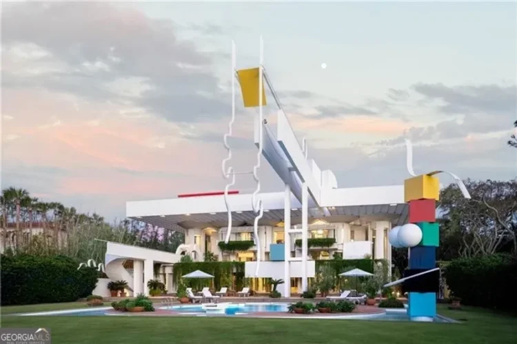 A large house with a prominent sculpture displayed in front of it.