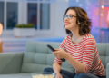 A woman looking happy while watching TV on a sofa