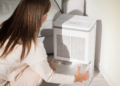A woman examines a white air conditioner.