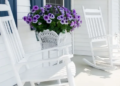 Two rocking chairs and a bouquet of flowers on a cottage porch