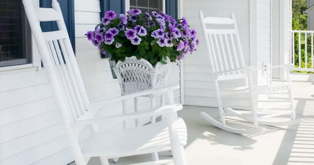 Two rocking chairs and a bouquet of flowers on a cottage porch