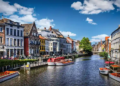 A scenic canal lined with boats gently floating on the water under a clear blue sky.