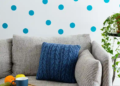 A cozy couch adorned with colorful pillows and a small green plant resting on its armrest.
