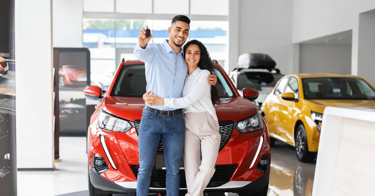 A couple stands in front of a new car