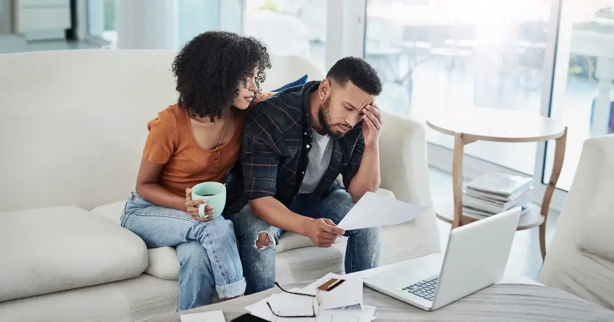 A couple looks at their finances on their couch.