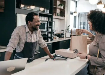 A cashier talks with a customer at the counter of a cafe.