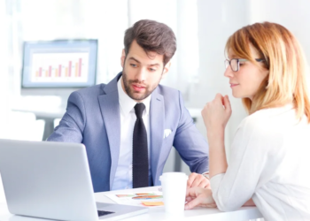 A banker shows a woman a computer screen.