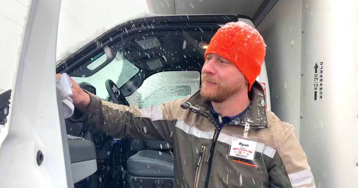 A U-Haul employee stands next to an open door on
the driver side of a U-Haul truck rental in the middle of a snowstorm.