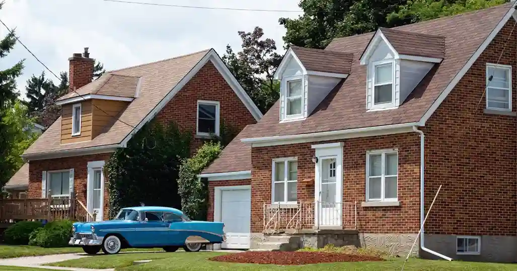 An old car in front of an old home.