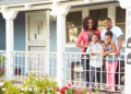 A family stands on a porch outside