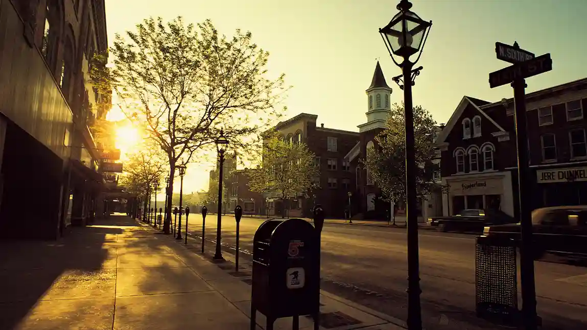 A street lamp illuminating a sidewalk at dusk, casting a warm glow on the surrounding area.