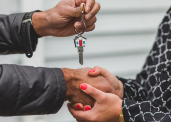 A person handing someone else a pair of house keys.