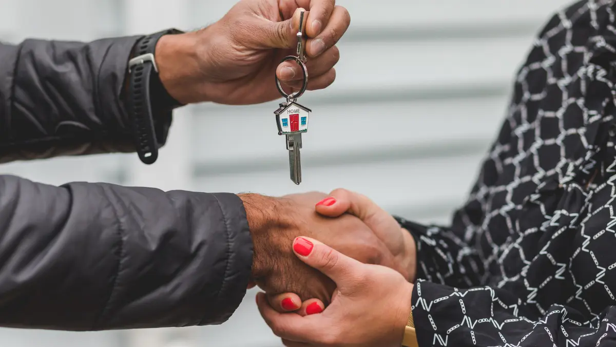 A person handing someone else a pair of house keys.