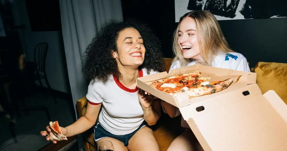 Two friends eating pizza