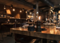 Cozy restaurant interior with dim lighting and elegant decor. Wooden tables are set with wine glasses, candles, and a pepper grinder, exuding a warm, inviting ambiance.