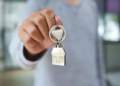 person holding keys with a house keychain