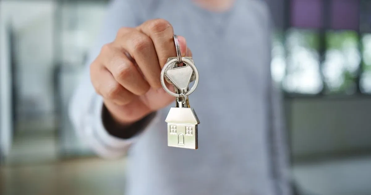 person holding keys with a house keychain