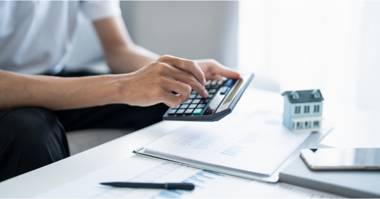 Man typing on a calculator with house figure beside him