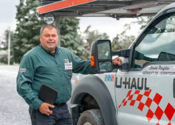 A U-Haul employee stands in front of a U-Haul vehicle in the snow in Canada.