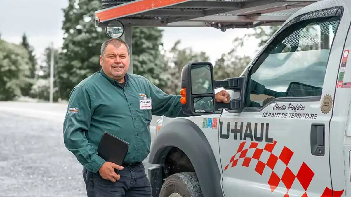 A U-Haul employee stands in front of a U-Haul vehicle in the snow in Canada.