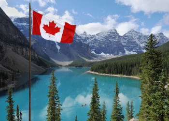Canadian flag in front of lake and mountains